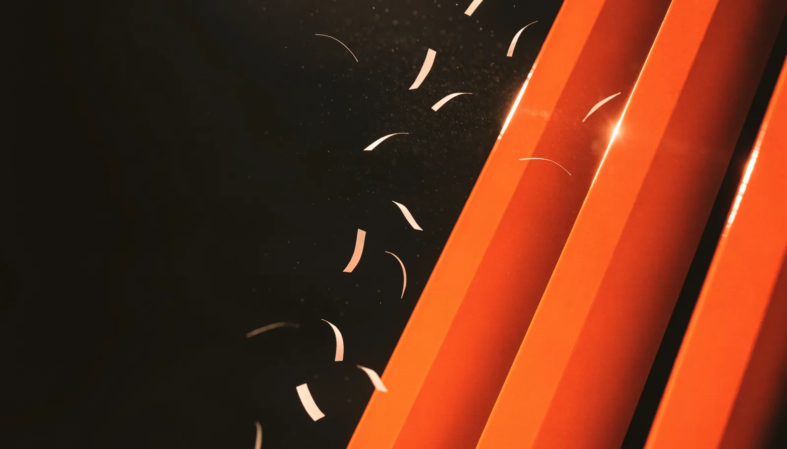 Three signal-orange lacquered slabs slicing diagonally through black space